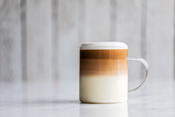 Cafe latte macchiato layered coffee in a see through glass cup on white background.