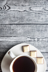 White cup with coffee on a white saucer on a gray wood background