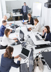 High-angle view of coworkers workin and communicating together in modern open plan office