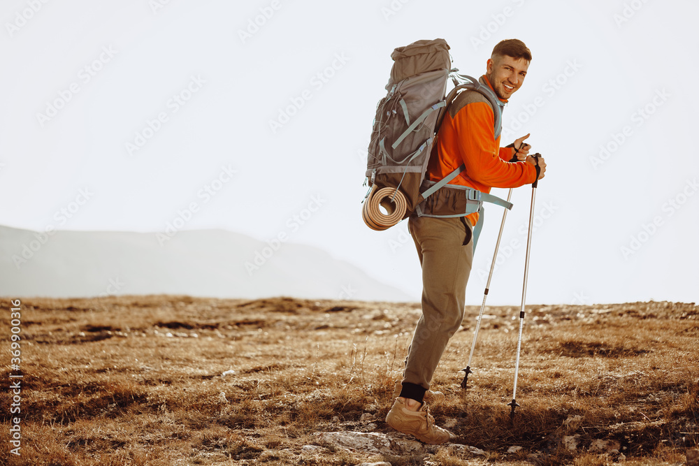 Man traveler with trekking sticks going up the mountain - obrazy, fototapety, plakaty 
