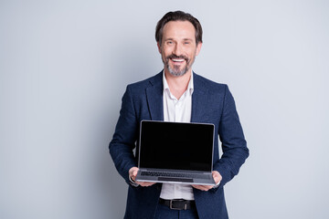 Photo of confident cheerful aged mature business guy hold computer netbook notebook showing customers novelty device model sale offer low price wear blue suit isolated grey background