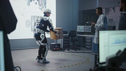 Poster - In Development Laboratory: Engineers Look at Robotics Exoskeleton Prototype Presentation with Person Testing it, Lifting Heavy Carboard Box. Designing Wearable Exosuit to Help Warehouse Workers