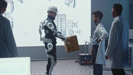 Aufkleber - In Development Laboratory: Engineers Look at Robotics Exoskeleton Prototype Presentation with Person Testing it, Lifting Heavy Carboard Box. Designing Wearable Exosuit to Help Warehouse Workers