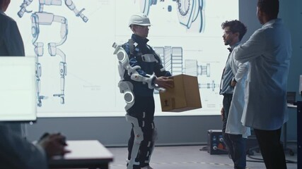 Leinwandbilder - In Development Laboratory: Engineers Look at Robotics Exoskeleton Prototype Presentation with Person Testing it, Lifting Heavy Carboard Box. Designing Wearable Exosuit to Help Warehouse Workers
