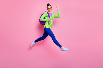 Wall Mural - Full length photo of cheerful high school girl hold backpack jump run go lesson greet teacher classmates wear green shirt blue pants trousers isolated over pastel color background