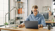 © Gorodenkoff - Handsome Young Man in Glasses and Shirt is Working on a Laptop in a Creative Business Agency. They Work in Loft Office. Diverse People Working in the Background. He's in Good Mood.