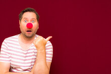 The Happy Surprised Charming Trendy And Smiling Man On Red Nose Day Or April Fools Day.Man Shows To The Side