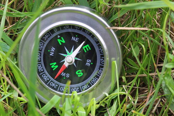 round compass on background of summer grass as symbol of tourism with compass, travel with compass and outdoor activities with compass