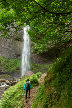 Woman Hiking Towards Waterfall In The The Pacific Northwest.