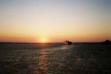 A Ferry In The Distance, Leaving The Port The Sunset.