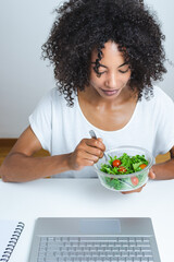 beautiful young afro woman eating salad in office