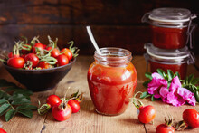 A Jar Of Rose Hip Jelly And Fresh Rose Hips