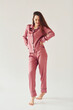 © standret - Cheerful young woman in pajamas standing indoors against white background in the studio