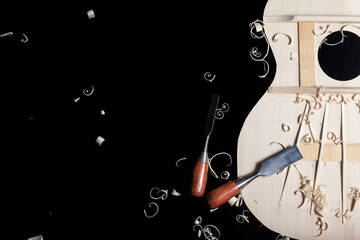 Sound top of guitar under construction with chisels and wood chips