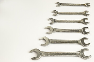 Six different wrenches lie on the right on a white background