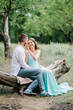 © omelnickiy - happy guy in a white shirt and a girl in a turquoise dress are walking in the forest park