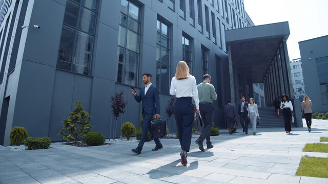 multi-ethnic young business persons corporate workers walking outside company in modern district dow
