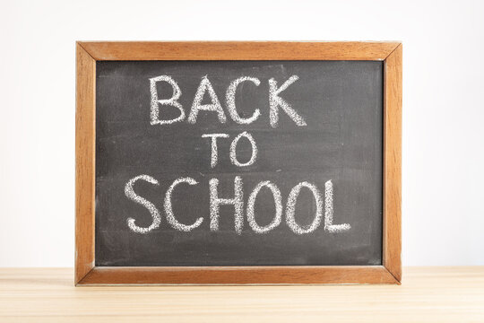 Back to school concept. Chalkboard with handwritten text on table