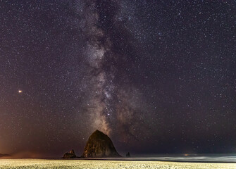 Wall Mural - Milky Way shines in the sky behind Haystack Rock on Cannon Beach in Oregon