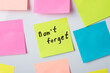 Sticky note with text Don't forget among other notes on a whiteboard in the office