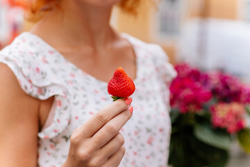 A girl is holding strawberry with a blur background