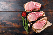 Organic bio sliced raw pork meat set over old rustic dark wood table with herbs and ingrefients top view space for text.