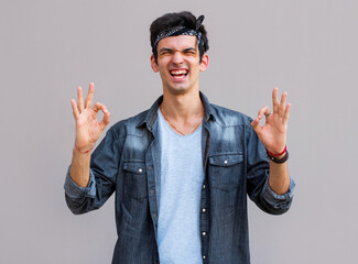 Wall Mural - Young man doing a double ok gesture with his hands.