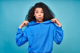 Fototapeta  - A funny teenage girl in a casual blue sweatshirt making grimaces.