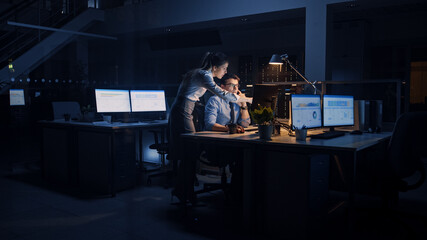 Poster - Ambitious, Confident Businessman Uses Desktop Computer, His Female Project Manager Explains Specific Tasks, Account Handling and Strategic Moves. Professional People Late at Night in Corporate Office