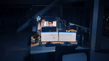 Aufkleber - Ambitious and Confident Businessman Uses Desktop Computer, His Female Project Manager Explains Specific Tasks, Account Handling and Strategic Moves. Professional People Late at Night in Big Office