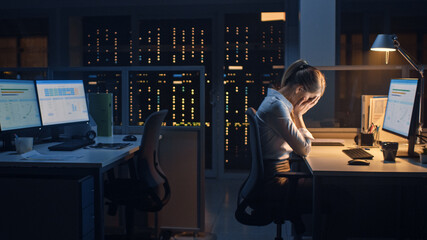 Poster - In the Office at Night, Overworked Tired Female Worker Uses Desktop Computer Closing Her Face with Arms. Tired Frustrated Exhausted Businesswoman Falls asleep at Her Job