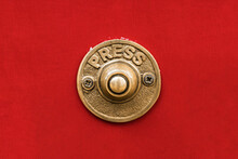 Classic Traditional Rustic Heavy Cast Brass Doorbell Button On A Seamless Red Wall Shot Straight On.