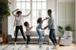 © fizkes - Overjoyed african American family with two little kids have fun dancing jumping together in living room, happy young ethnic parents with small children engaged in funny activity at home on weekend