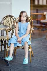 little girl sitting in a chair at a restaurant in summer