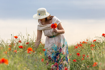 Woman in a white dress posing in a poppy garden