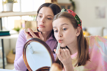 Poster - Cute teenage girl with long blond hair applying lipstick and looking in mirror