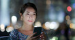 © leungchopan - Woman use of mobile phone in city at night
