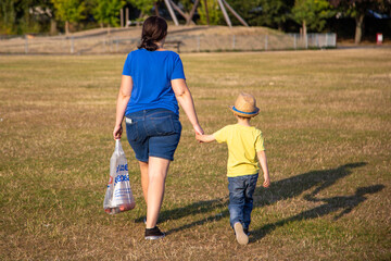 A Mother and son walking through a park holding hands