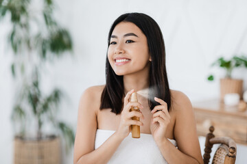 Wall Mural - Pretty happy asian girl applying hair oil at home