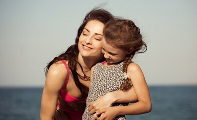 Wall Mural - Enjoying beautiful mother hugging her playful fun kid girl on vacation sea summer holidays. Closeup outdoor