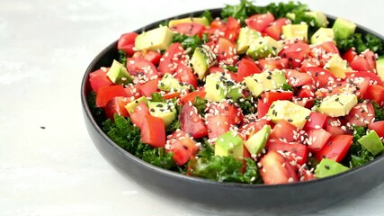 Sticker - Kale salad with tomatoes and avocado in black plate. Healthy raw vegan lunch concept.