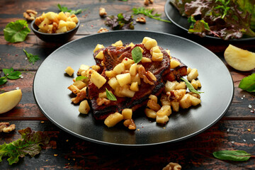 Wall Mural - Roasted Pork chops with caramelized apples, walnuts and sage in black plate on wooden table