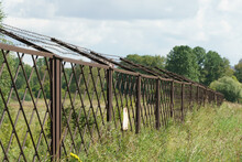 Old Rusty Fence With Rusty Barbed Wire Installed In The Field And Extending Into The Distance, Warning Sign