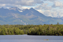 A Family Kayaks Across Wasilla Lake, Alaska, On A Sunny Summer Day.