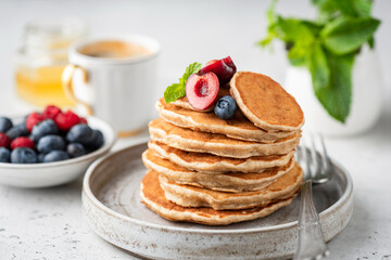 Wall Mural - Healthy oat pancakes with berries on a craft ceramic plate. Vegan breakfast food