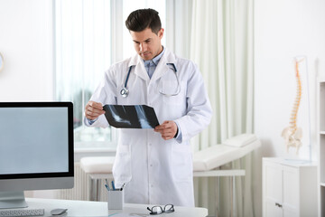 Canvas Print - Professional orthopedist examining X-ray picture in clinic