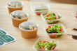 Background image of healthy food portions ready for packaging on wooden table in small food delivery service, copy space
