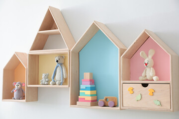 Wall Mural - Different house shaped shelves with toys on white wall. Interior design