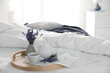 © New Africa - Wooden tray with cup of fresh hot tea and beautiful lavender flowers on bed, space for text. Tasty breakfast