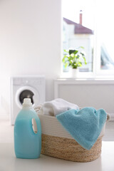 Poster - Wicker basket with towels and detergent on white table indoors. Space for text